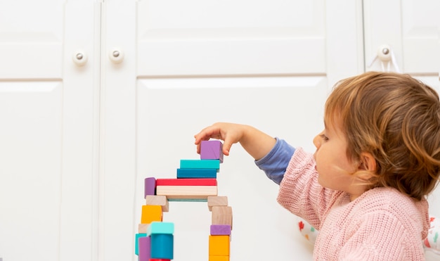 Fille enfant mignonne et charmante à la maison, jouant avec des jouets de blocs de construction en bois.