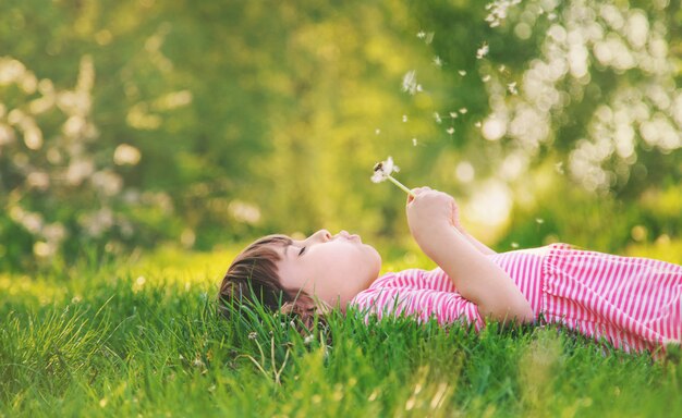 Fille enfant avec des pissenlits dans le parc. Mise au point sélective.