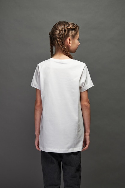 Fille enfant portant un t-shirt blanc avec un espace pour votre logo ou votre design en studio sur fond gris