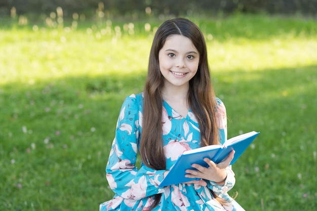 Fille enfant se détendre à l'extérieur avec un livre, concept de littérature classique.