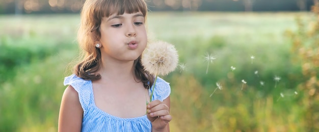 Fille enfant soufflant un pissenlit