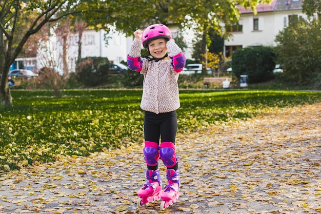 Fille enfant souriante dans un casque en rollers de protection dans le parc