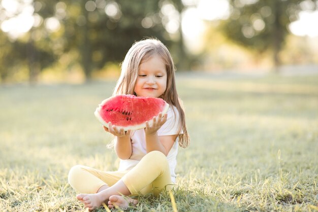 Fille d'enfant de sourire mangeant la pastèque mûre