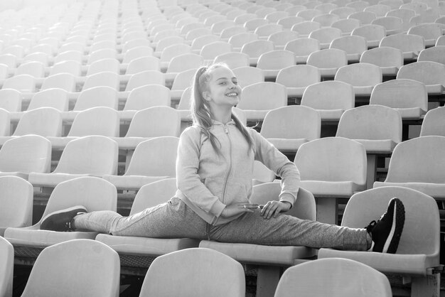 Fille enfant sport d'entraînement à l'extérieur sur la tribune du stade s'asseoir dans la forme physique divisée