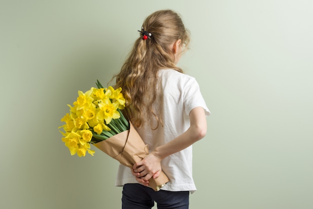 Fille enfant tenant le bouquet de fleurs jaunes.