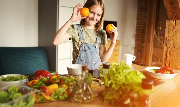 Photo fille enfant tenant des oranges à la cuisine et souriant joli enfant féminin avec des agrumes et