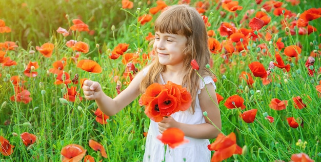 Fille d'enfants dans un champ avec des coquelicots.