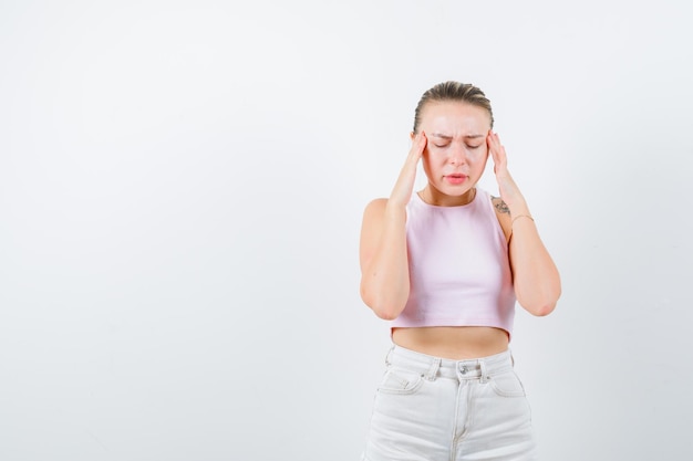 La fille ennuyée montre son mal de tête sur le fond blanc