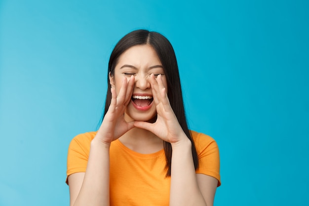 Fille enthousiaste asiatique insouciante criant un ami d'appel interurbain brisant des émotions libres criant...