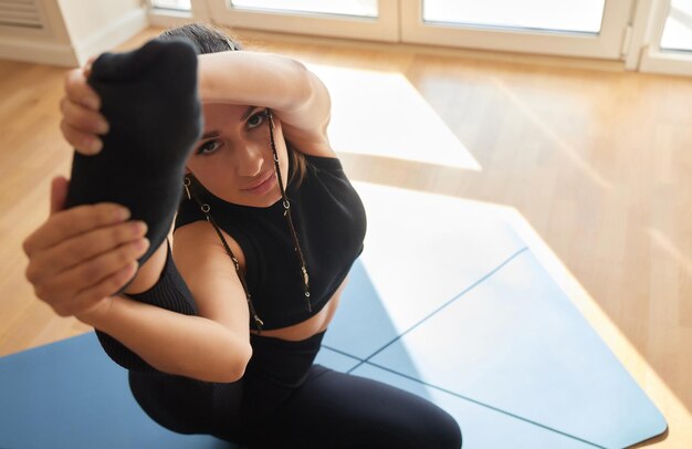 Photo une fille d'entraînement physique s'accroupit sur le tapis à la maison, vue de côté