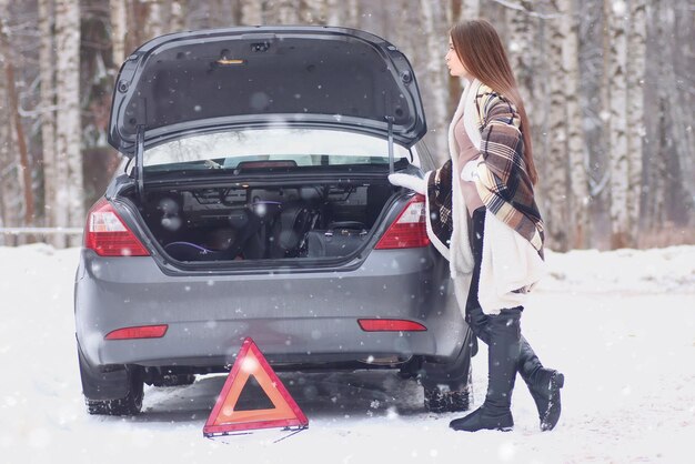 Fille enveloppée dans une couverture placée près de la voiture cassée attendant de l'aide