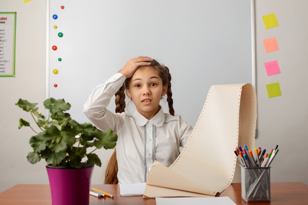 Fille épuisée montrant la liste des tâches à faire, choquée par la quantité de travail, exprimant sa surprise et son étonnement