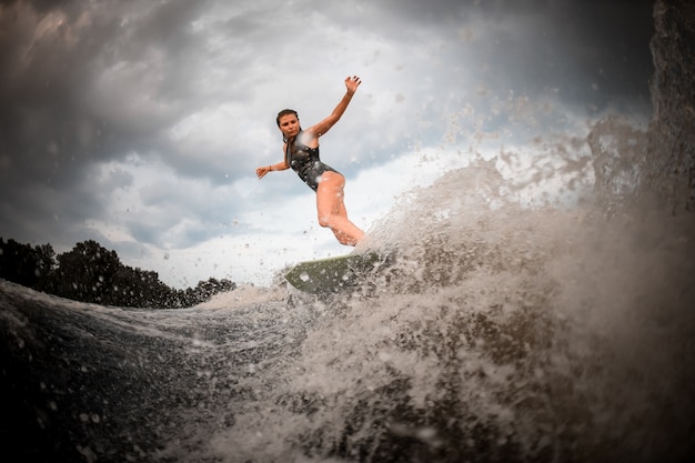 Fille, équitation, sur, les, wakeboard, sur, les, rivière, dans, les, fond, arbres, monter mains