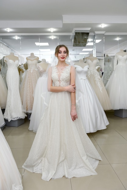 Fille essayant une robe de mariée dans un salon, debout en arrière