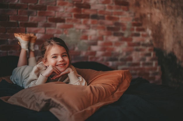 la fille est allongée sur le lit sur le fond d'un mur de briques