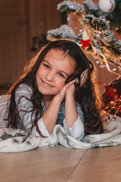 la fille est allongée et rit sous le sapin de Noël