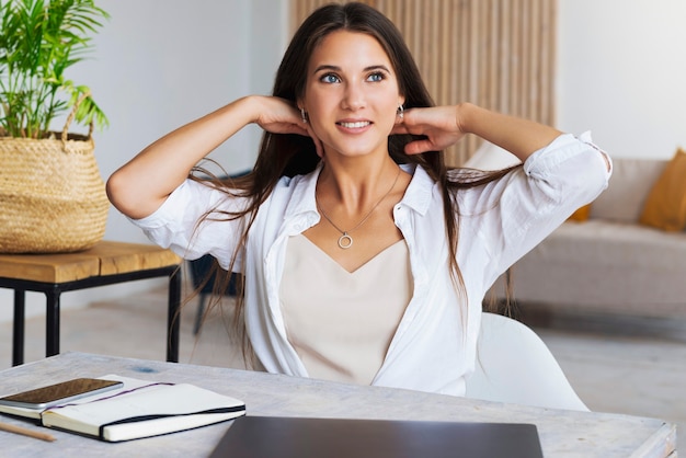 Fille est assise au bureau dans le bureau à domicile et montre un geste joyeux avec ses mains.