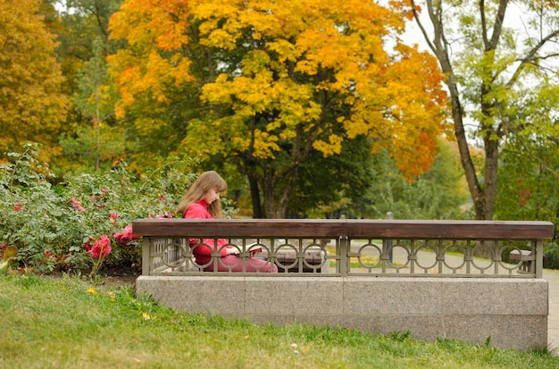 Fille est assise sur un banc et livre de lecture, automne.