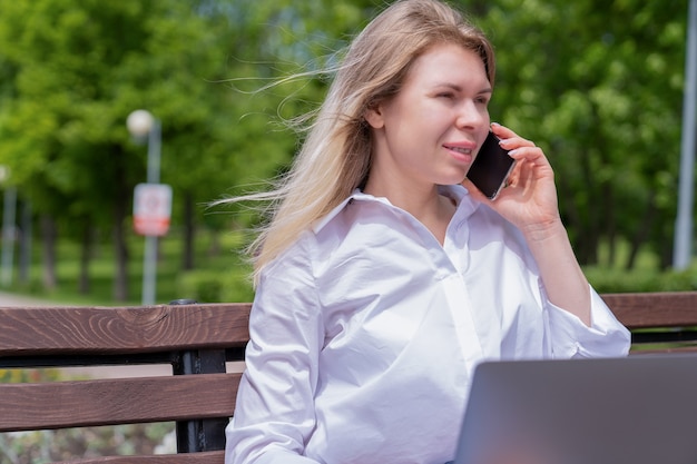 Une fille est assise sur un banc de parc un jour d'été