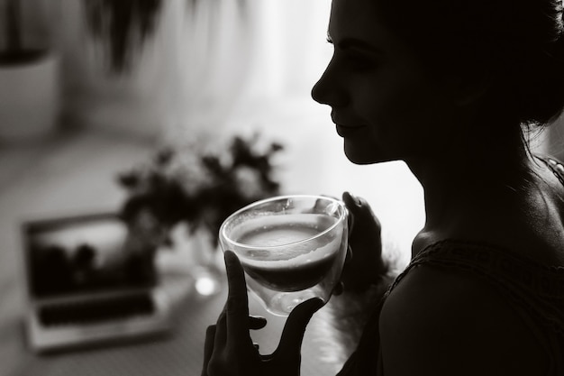 fille est assise confortablement sur le canapé et boit du café