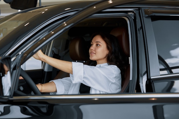 Une fille est assise dans une nouvelle voiture chez un concessionnaire automobile