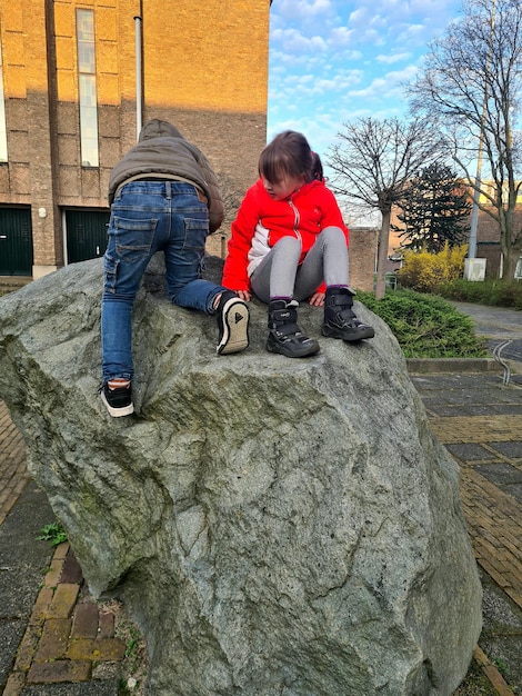 Une fille est assise sur un rocher, dos à la caméra