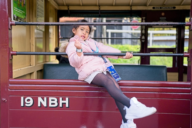 Une fille est assise sur un train rouge avec les lettres nnh sur le côté.