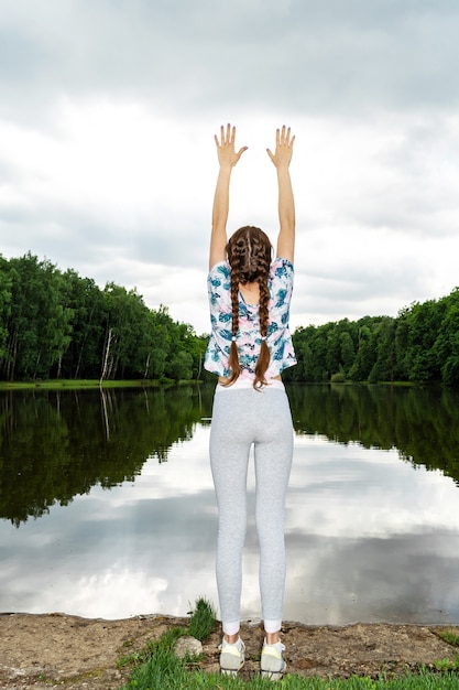 La fille est engagée dans le yoga sur le lac.