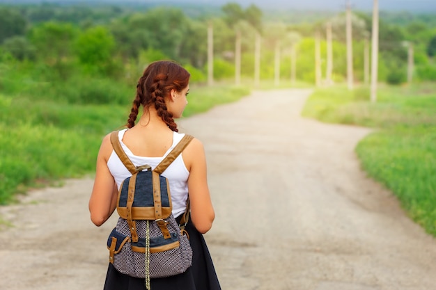 La fille est sur la route avec un sac à dos