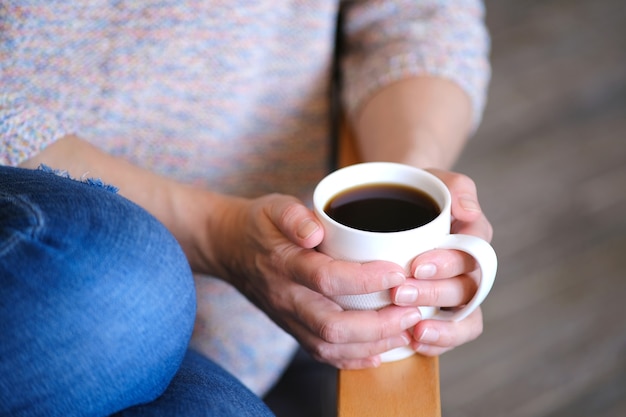 Fille était assise confortablement sur une chaise tenant une tasse de café