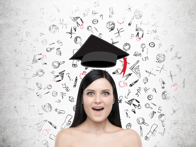 Fille étonnée avec un chapeau de graduation en lévitation et des croquis d'éducation