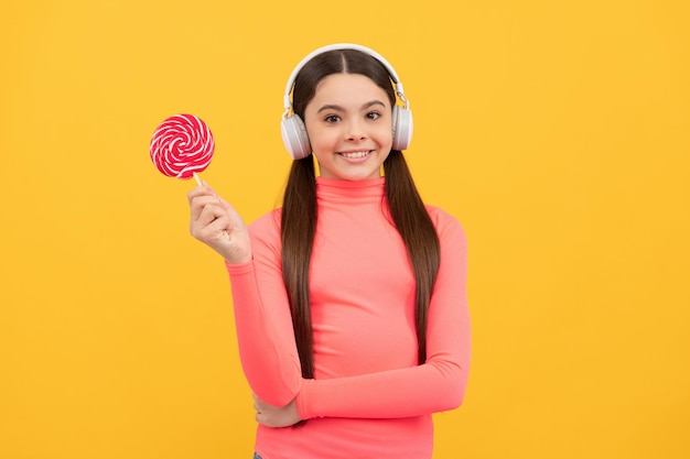 Fille étonnée tenir sucette écouter de la musique sucette enfant enfant dans un casque tenir sucette