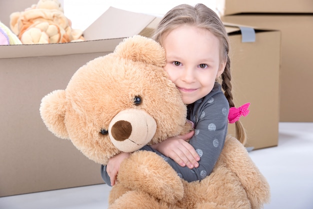 Fille étreignant un gros ours à la maison et souriant.