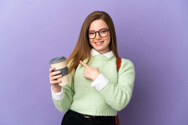 Fille étudiante adolescente sur fond violet isolé pointant vers le côté pour présenter un produit