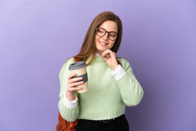 Fille étudiante adolescente sur fond violet isolé regardant sur le côté et souriant