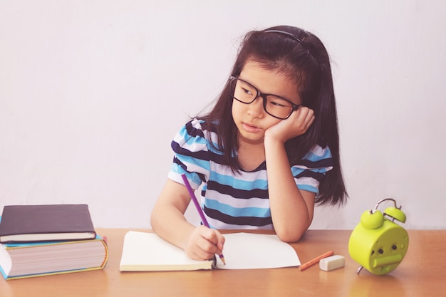 Fille étudiante asiatique s'ennuie et fatiguée à faire ses devoirs