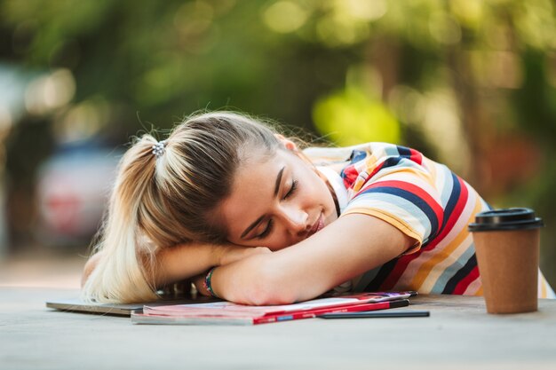 Fille étudiante assise dans le parc dormir