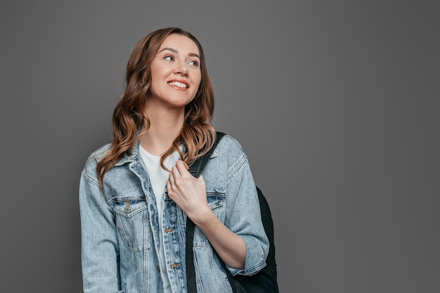 Fille étudiante caucasienne sur fond gris à la recherche de suite