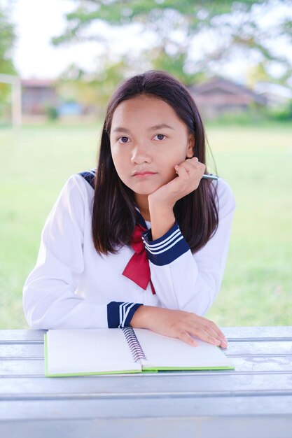 Fille étudiante heureuse avec emplacement de livre à la porte extérieure à l'école, fille asiatique.