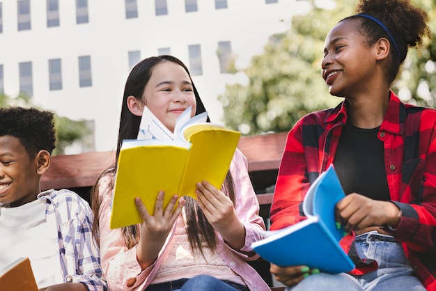 Fille étudiante lisant un livre avec un ami au parc de l'école