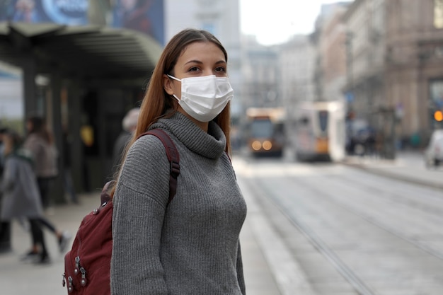 Fille étudiante avec masque de protection en attente des transports publics dans la rue