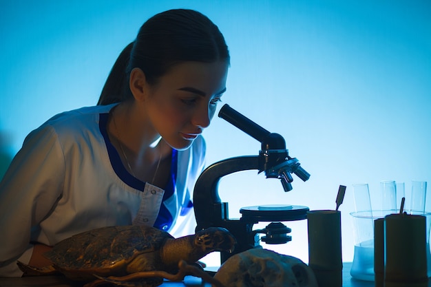 Fille étudiante à la recherche dans un microscope, concept de laboratoire scientifique.