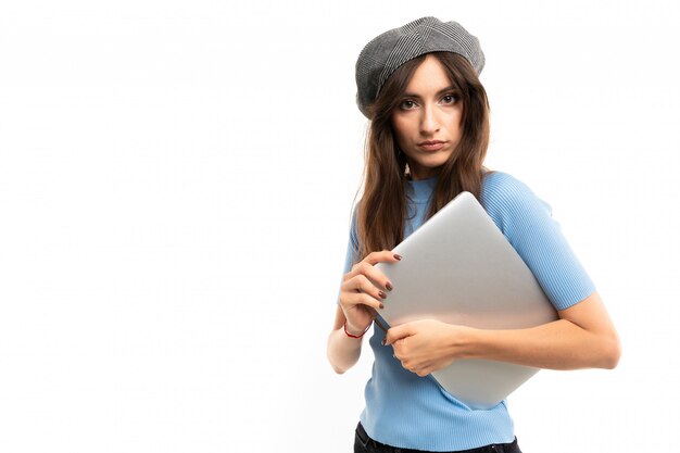 Fille européenne avec un ordinateur portable fermé en mains sur un mur blanc