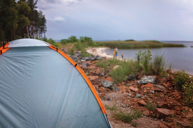 Photo fille évasion locale enfants avec le père se reposant près de la tente de camping sur le terrain de camping temps nuageux