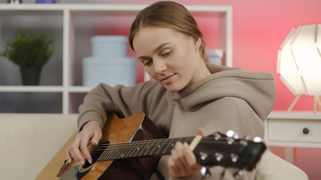 Fille excitée jouant de la guitare acoustique dans le salon Heureux musicien jouant des accords instrument à cordes