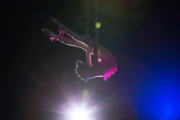 La fille exécute des éléments acrobatiques dans l'air Gymnaste de cirque sur scène