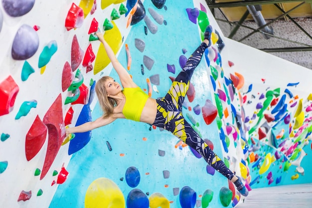 Une fille exécute un tour sur un mur d'escalade