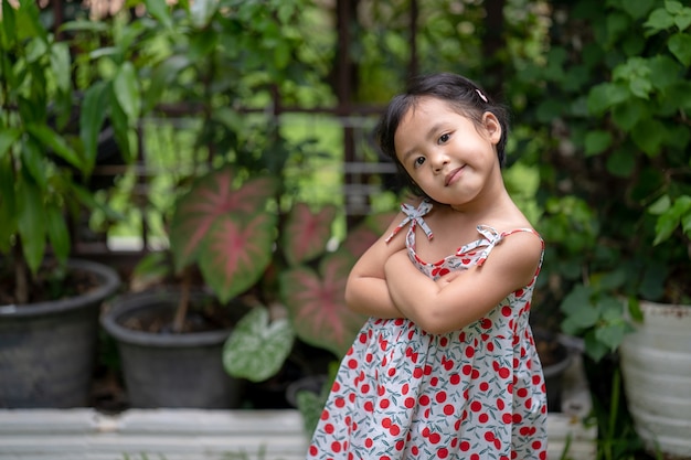 Fille avec l'expression du visage heureux debout les bras croisés au jardin