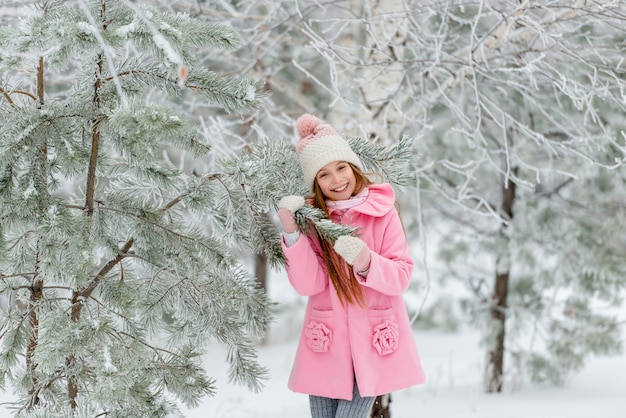 Fille à l'extérieur en hiver près de sapin de Noël