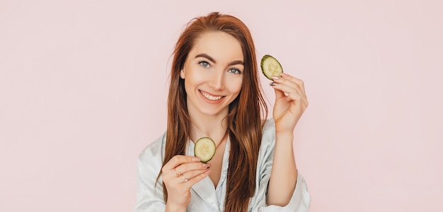 Une fille fabrique des masques de beauté pour le visage faits maison. Concombres pour la fraîcheur de la peau autour des yeux